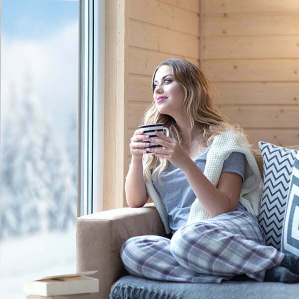 Women in indoor wearing pajama and sweater with a cup of coffee